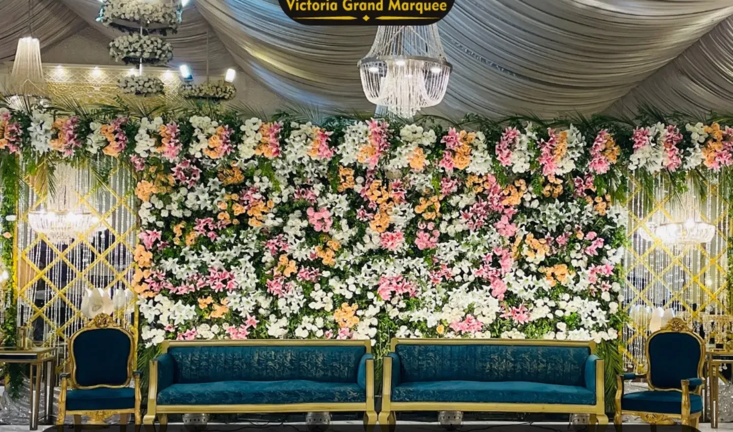 Barat stage with a full floral wall and gilded seating at Victoria Grand Marquee